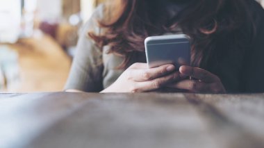 Portre resim tutarak ve akıllı telefon vintage Cafe ahşap masa saati kullanılarak bir kadının elleri