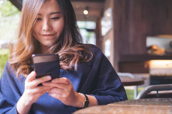 Kullanarak Modern Loft Kafede Siyah Bir Akıllı Telefon Bakarak Gülen — Stok fotoğraf