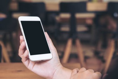 Hareket eden telefon boş siyah perde ile modern loft kafede tutan bir kadın görüntüsünü mockup