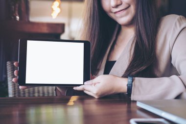 Holding ve modern kafede siyah tablet pc boş beyaz ekran ile gösterilen bir güzel Asya iş kadını mockup görüntü