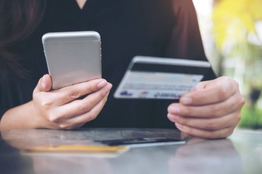 Kredi kartı tutan ve ofiste tabloda cep telefonuyla bir kadının el portre resim