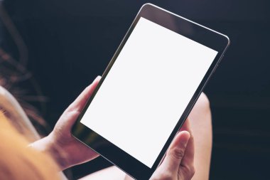 Modern kafede uyluk ile beton zemin arka plan üzerinde siyah tablet pc boş beyaz ekran ile holding kadının eller mockup görüntü