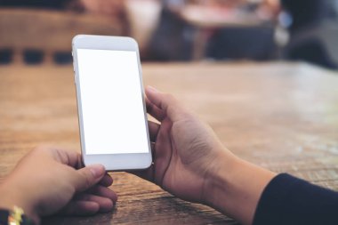 Mockup görüntü tutarak ve ahşap masa arka plan boş ekran ile beyaz cep telefonu kullanarak kadının el