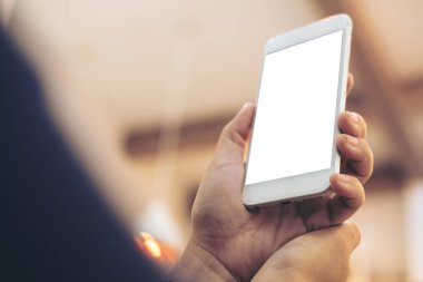 Mockup görüntü tutarak ve beyaz cep telefonu ile vintage kafede boş perde yükselterek eller