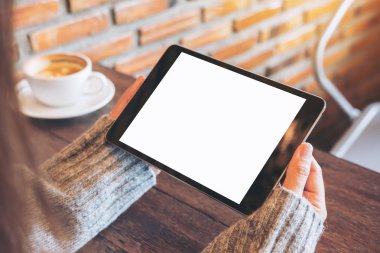 Kafede siyah tablet pc ile beyaz kahve Kupası tahta masada boş beyaz ekran ile holding eller mockup görüntü