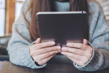 Portre resim bir kadın tutarak ve modern kafede oturan tablet PC'yi kullanma