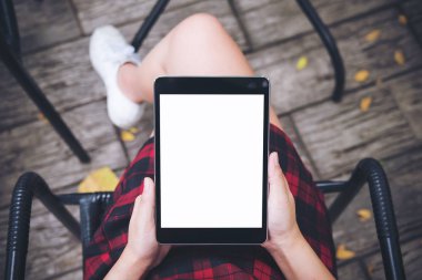 Kadının el vintage kafede uyluk ile ahşap zemin arka plan üzerinde siyah tablet pc boş beyaz ekran ile tutarak mockup üstten görünüm görüntüsü 