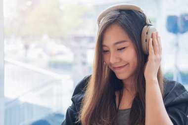 Portre resim güzel bir Asya kadının zevk hissi ile modern Cafe kulaklık ile müzik dinlemek rahatla ve mutlu