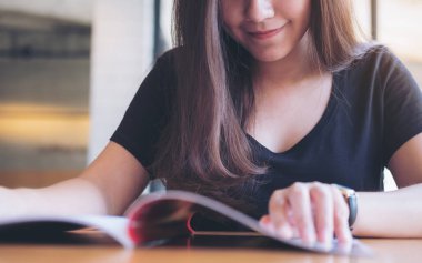 Portre resim güzel bir Asya kadının modern kafede bir kitap okuma 
