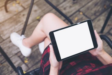 Vintage kafede uyluk ile ahşap zemin arka plan üzerinde siyah tablet pc boş beyaz ekran ile holding kadının eller mockup görüntü