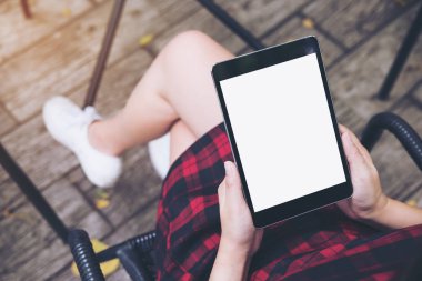 Vintage kafede uyluk ile ahşap zemin arka plan üzerinde siyah tablet pc boş beyaz ekran ile holding kadının eller mockup görüntü
