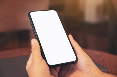 Masada dizüstü bilgisayarlı ve boş masaüstü ekranlı siyah cep telefonu tutan ellerin görüntüsü