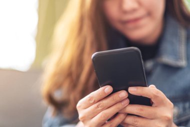 Güzel bir Asyalı kadının elinde tuttuğu, kullandığı ve baktığı yakın plan görüntüsü.