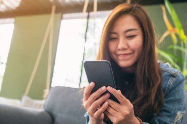 Güzel bir Asyalı kadının elinde tuttuğu, kullandığı ve baktığı yakın plan görüntüsü.