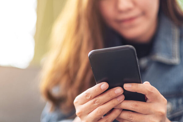 Крупный план изображения красивой азиатской женщины, держащей, используя и глядя на смартфон