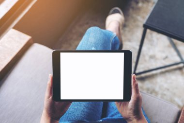 Kafede otururken elinde boş beyaz ekran olan siyah tabletli bir kadının üst görünüm görüntüsü