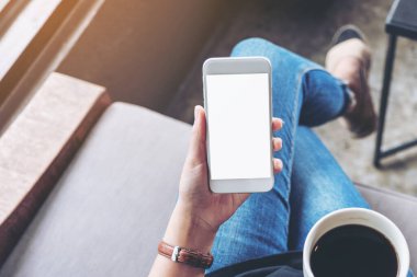 Kafede oturup kahve içerken elinde boş ekranla beyaz cep telefonu tutan kadının en iyi görüntüsü.