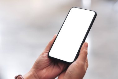 Siyah cep telefonunu boş masaüstü ekran ile tutan kadınların ellerinin görüntüsü