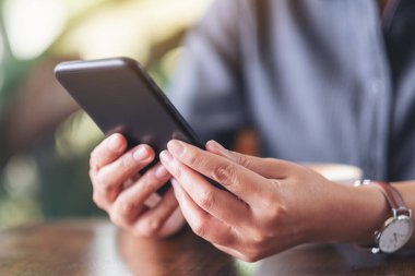 Elinde tutan, kullanan ve akıllı telefona bakan bir kadının yakın plan görüntüsü.