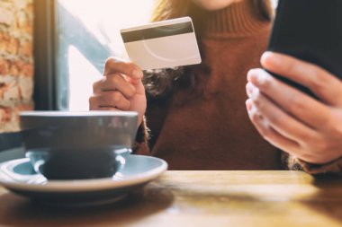 Cep telefonundan alışveriş yapmak ve satın almak için kredi kartı kullanan bir kadın