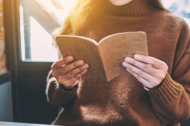 Yakından bakınca, elinde kitap tutan ve okuyan bir kadının görüntüsü. 