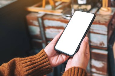 Boş masaüstü ekranı olan siyah cep telefonunu tutan ellerin görüntüsü