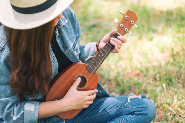 stock image A woman sitting and playing ukulele in the outdoors