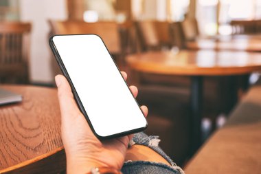 Masada dizüstü bilgisayarlı ve boş masaüstü ekranlı siyah cep telefonu tutan ellerin görüntüsü