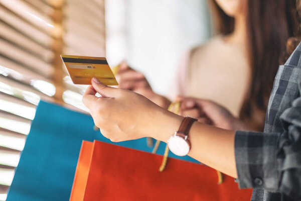 Women with shopping bags holding and using a credit card for purchasing