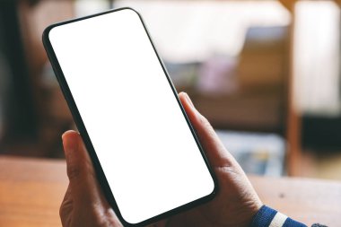 Boş masaüstü ekranı olan siyah cep telefonunu tutan ellerin görüntüsü