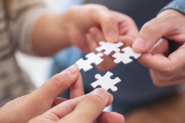 İnsanların el ele tutuşup yapboz parçalarını bir araya getirdikleri yakın plan görüntüler.