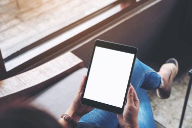 Kafede otururken elinde boş beyaz ekran olan siyah tabletli bir kadının üst görünüm görüntüsü