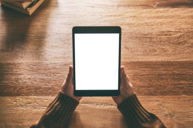 Elleri tutarken ve siyah tablet bilgisayar kullanarak tahta masanın üzerinde boş beyaz masaüstü ekran oluştururken üst görünüm görüntüsü