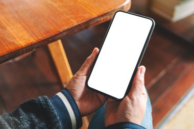 Boş masaüstü ekranı olan siyah cep telefonunu tutan ellerin görüntüsü