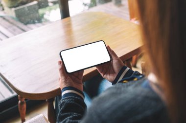 Boş masaüstü ekran ile siyah cep telefonu tutan bir kadının görüntüsü