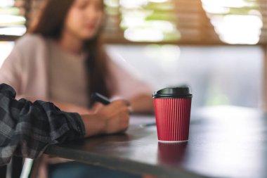 Arka planda iş adamı olan kağıt bir kahve fincanı.