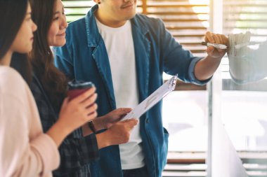 Bir grup iş adamı ofiste beyaz tahtayla fikirleri tartışıyor ve inceliyor.