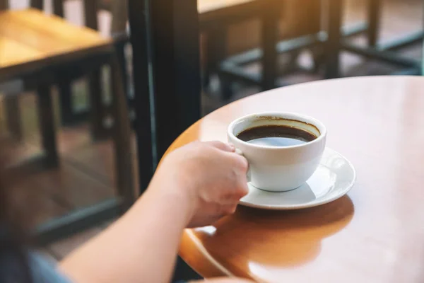 テーブルの上に熱いコーヒーを持っている手のクローズアップイメージ — ストック写真