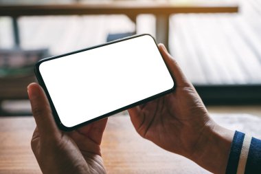 Boş masaüstü ekranı olan siyah cep telefonunu tutan ellerin görüntüsü