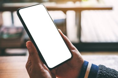 Boş masaüstü ekranı olan siyah cep telefonunu tutan ellerin görüntüsü