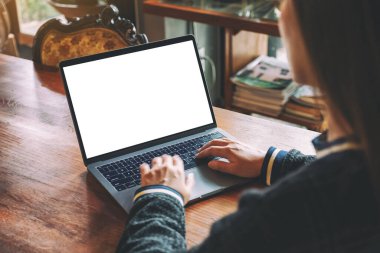 Laptop klavyesinde boş beyaz masaüstü ekran ve tahta masa üzerinde yazı yazan bir kadının görüntüsü