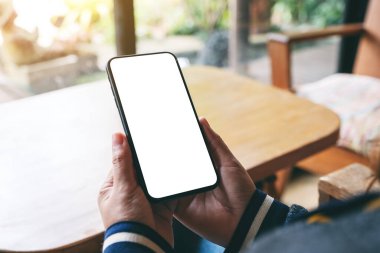 Boş masaüstü ekranı olan siyah cep telefonunu tutan ellerin görüntüsü