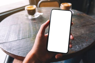 Bir el ele tutuşmanın ve kafede boş beyaz ekranlı siyah cep telefonunu göstermenin maketi.