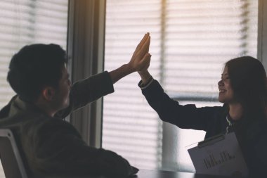 İki iş adamı birbirine beşlik çakmak için ellerini kaldırıyor. 