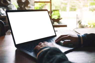 Laptop klavyesinde boş beyaz masaüstü ekran ve tahta masa üzerinde yazı yazan bir kadının görüntüsü