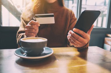 Cep telefonundan alışveriş yapmak ve satın almak için kredi kartı kullanan bir kadın
