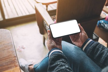 Boş masaüstü ekran ile siyah cep telefonu tutan bir kadının görüntüsü