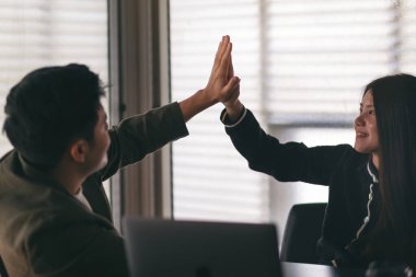 İki iş adamı birbirine beşlik çakmak için ellerini kaldırıyor. 