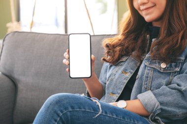 Kafede elinde siyah cep telefonu tutan ve gösteren bir kadının görüntüsü.