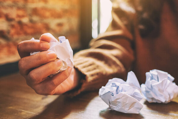 Крупный план женщины, испортившей бумагу вручную на деревянном столе
 